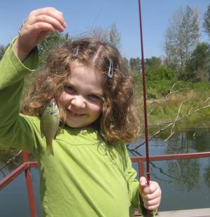 A girl with a small bluegill caught at St. Louis Ponds.