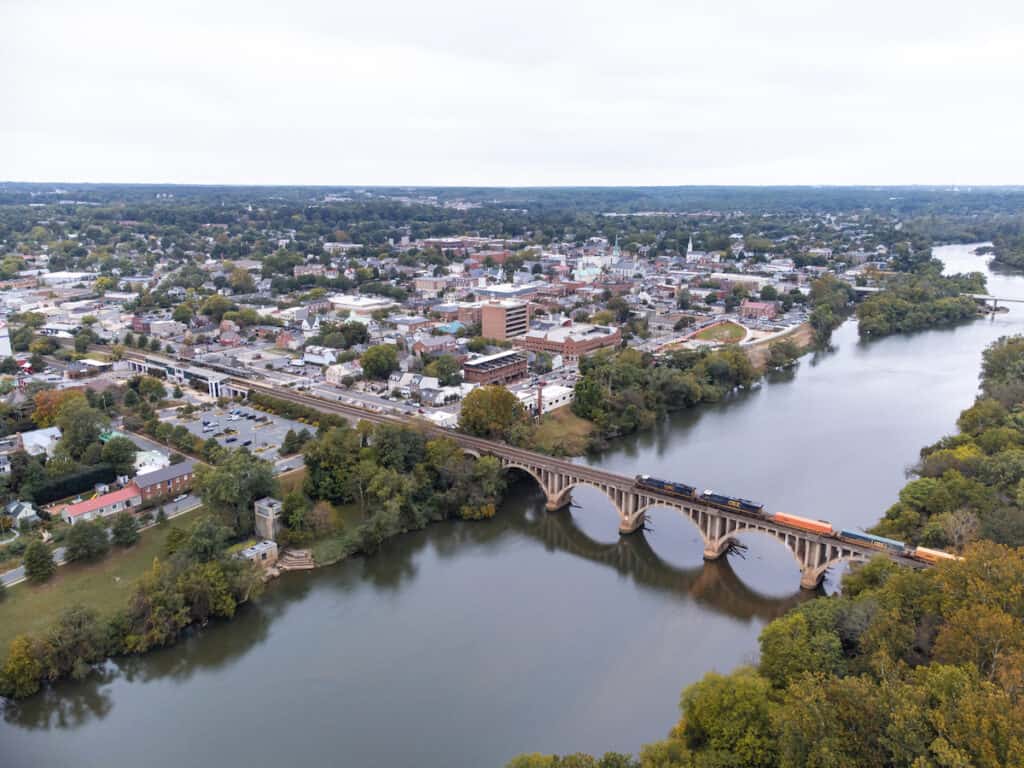 An aerial photo of downtown Fredericksburg, Virginia, with a train passing over the Rappahannock River, an excellent place to catch catfish.